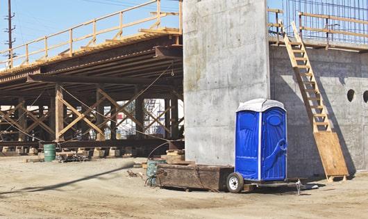 blue portable toilets arranged in a neat line on a construction site